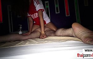 Asian teen sits on her clients back and massages him