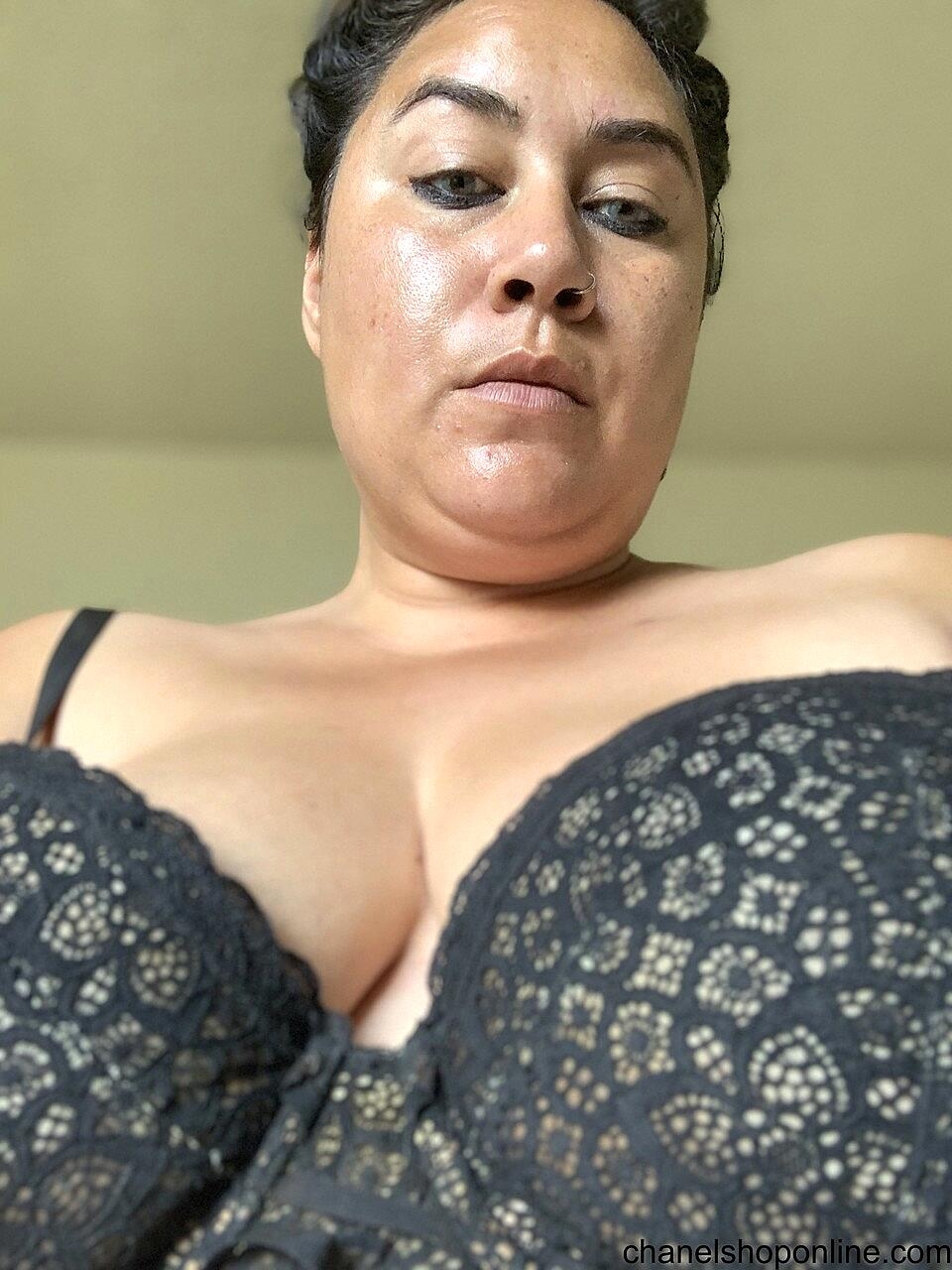 Angry mature woman poses in her bra and shows her sexy cleavage