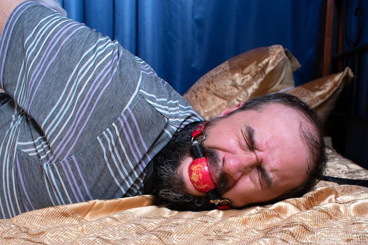 Brunette chick works over the soles of a restrained and ball gagged man