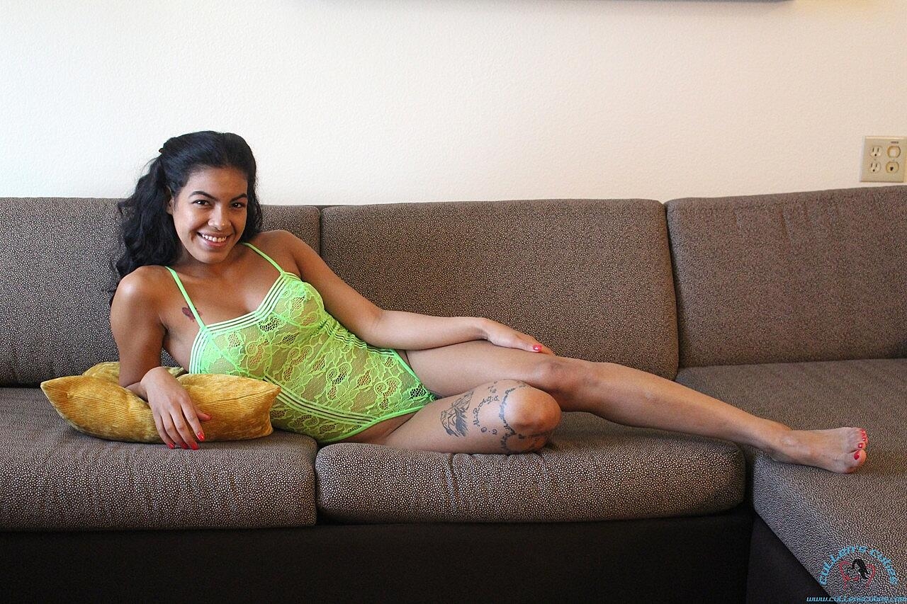 Dark-haired doll posing in her sexy fluorescent green lingerie on the sofa