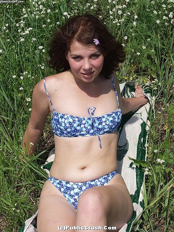 Young looking girl takes off her bikini to go naked amid wildflowers
